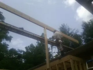 Carpenter setting a ridge beam over a new addition frame — Ice Dam Removal by Roofing Brothers in Four Oaks