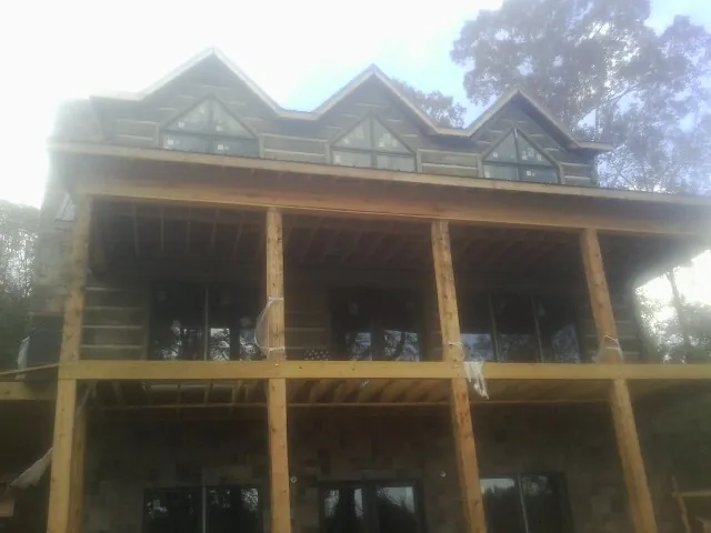 Dormers and porch framing on a large log home under construction — Roof Coating work by our crew in Four Oaks