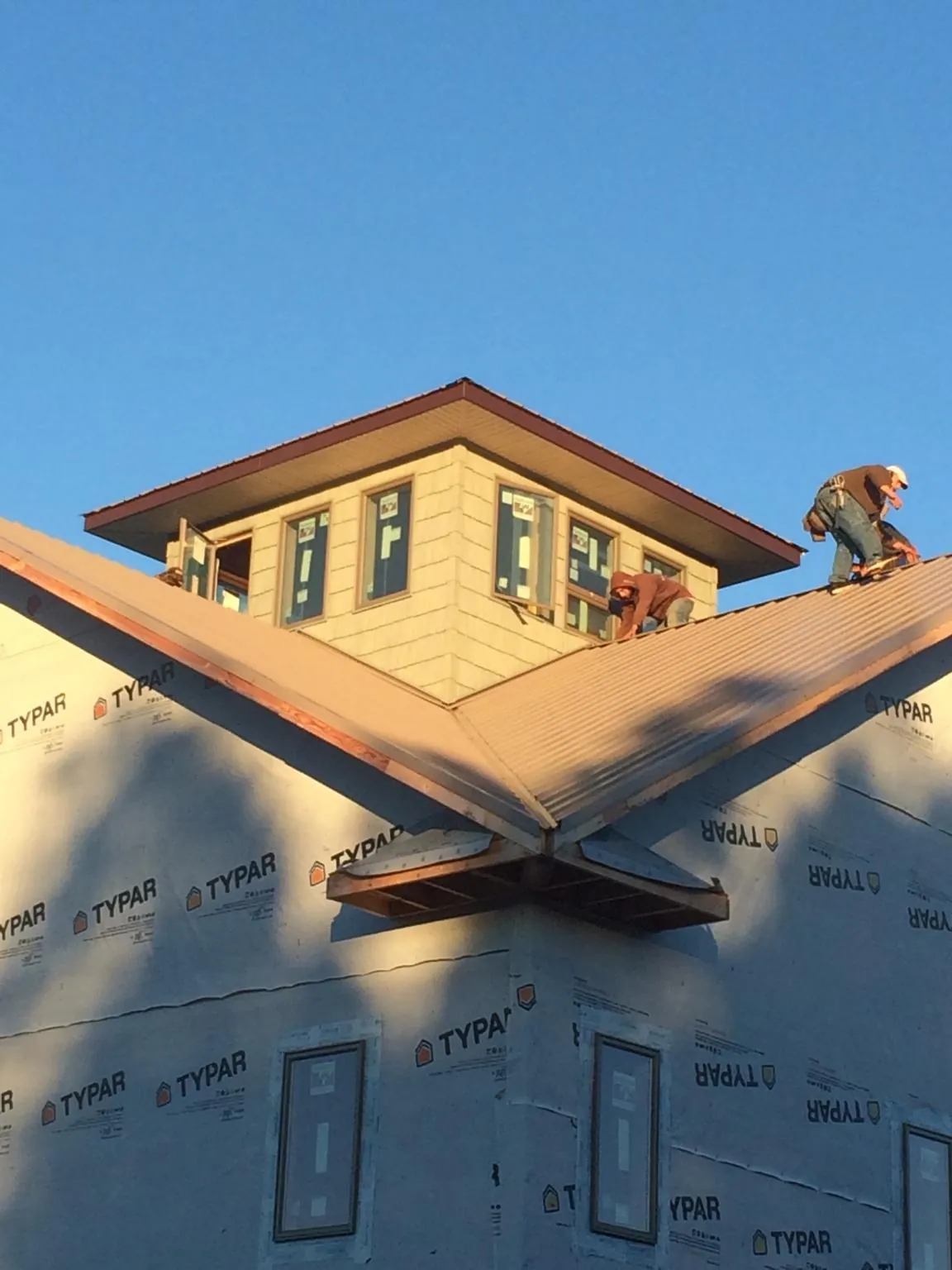 Roofers working around a rooftop cupola on a new metal roof at sunset — Roof Waterproofing in Four Oaks by Roofing Brothers